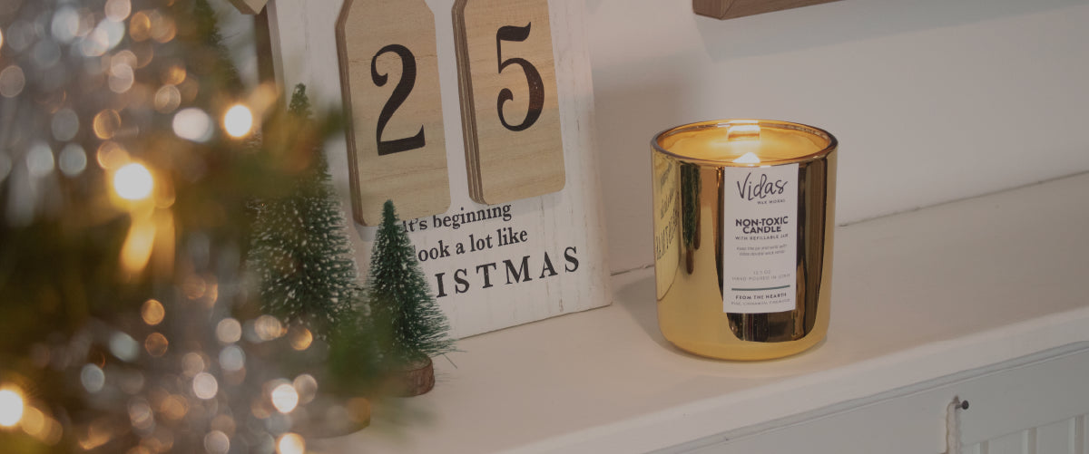 Gold candle on a shelf with Christmas decorations and a calendar in the background