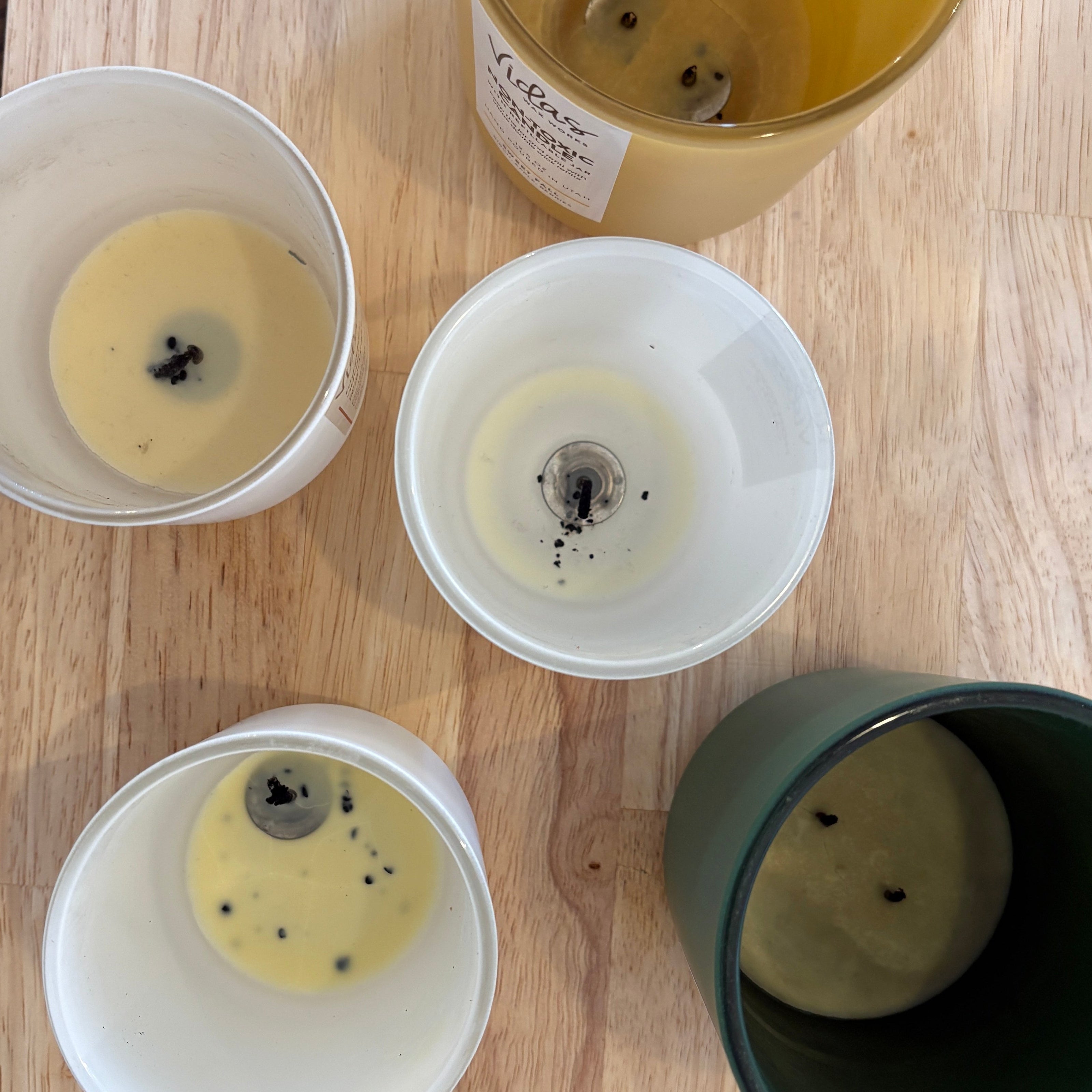 Five empty candle jars on a wooden tabletop