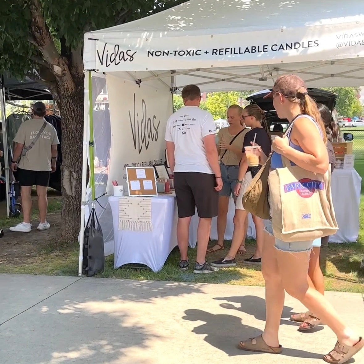 People at an outdoor event with a booth selling Violas candles.
