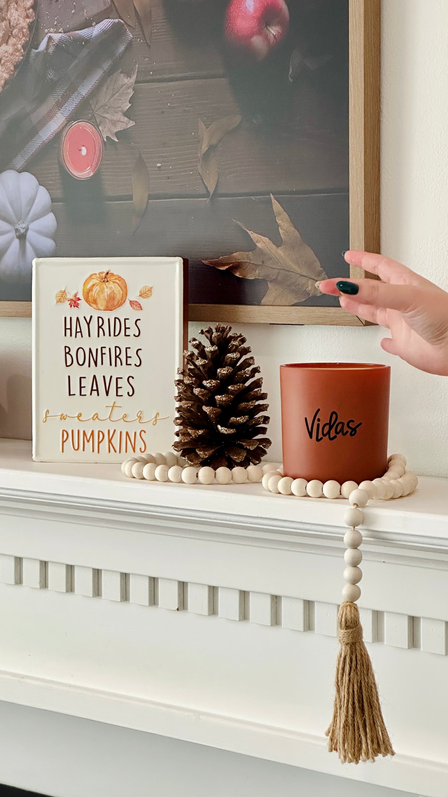 Fall elegance adorns the mantle with a clay candle jar at its center, embraced by seasonal decor. A hand gracefully inserts a candle refill into the jar, combining style and sustainability in a harmonious autumn display.